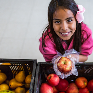 Hispanic girl holds apple.